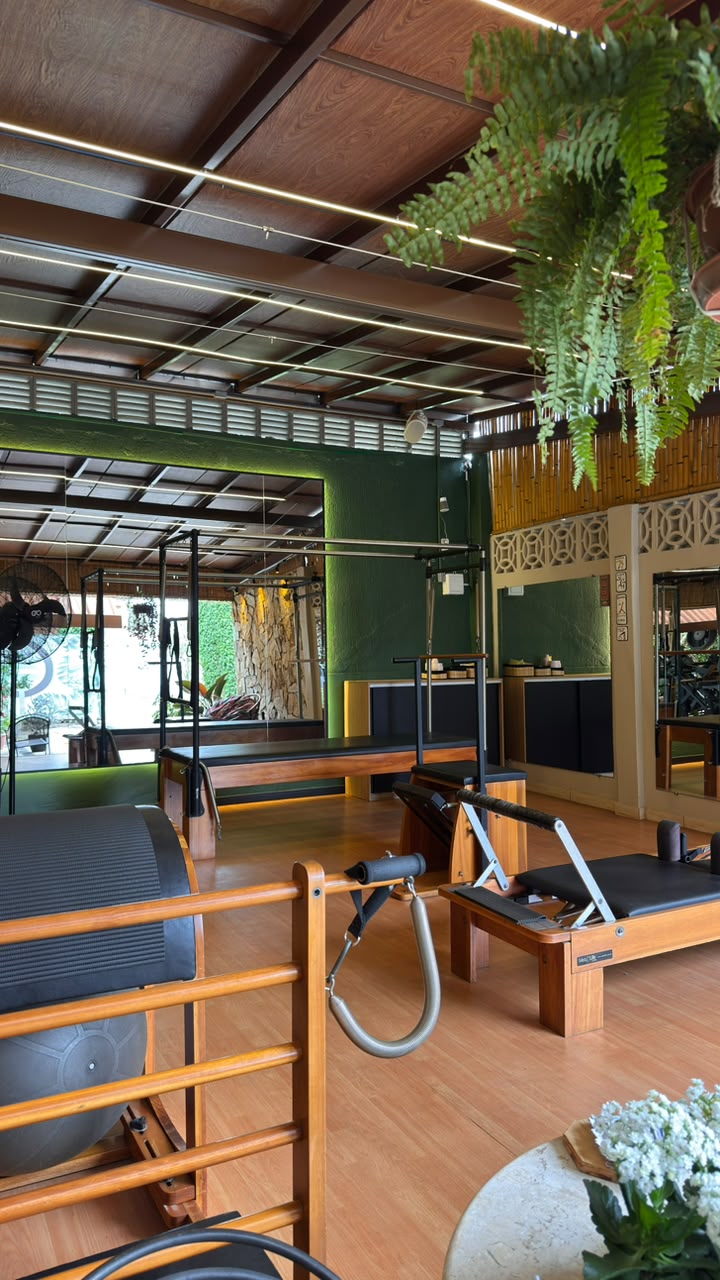 Estúdio de Pilates completo, com equipamentos de madeira e vista para o verde