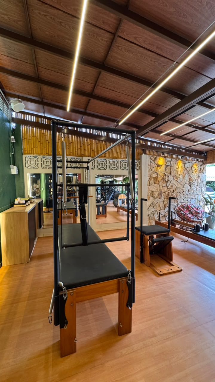 Reformer de Pilates com parede de pedra ao fundo